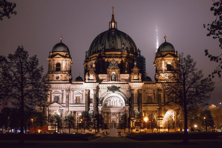 La catedral de Berlín iluminada en una noche de niebla, con la Torre de Televisión perdida en el cielo.