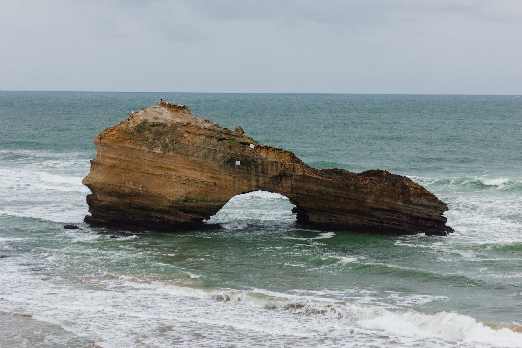 La roca de arenisca y su arco, con las olas del Atlántico pasando por debajo.